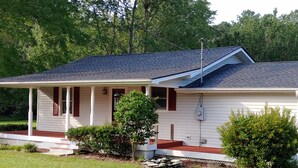 A single-story house with a covered porch, a small front yard, and a metal roof. - The Lake House at Turtle Cove: Cozy relaxing lake home with dock on wooded lot. (Eutawville)