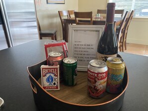 Una mesa con una bandeja negra que sostiene una botella, latas y cartas.