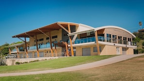 A modern two-story building with a flat roof, large windows, and a covered outdoor area.