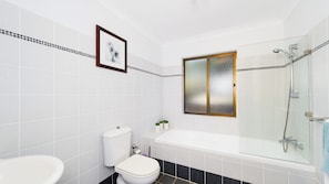 Een badkamer met toilet, wastafel en bad.