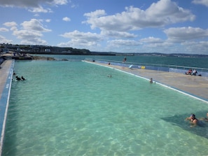 Une piscine à l’eau claire, un poste de surveillance pour les sauveteurs et quelques personnes qui nagent.