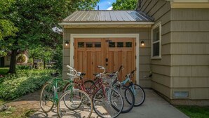A building with a garage door, a bicycle rack with several bicycles, and a well-maintained garden area. - Lake Street 425 ~ Fantastic 2bed/2bath Home Right (Sandpoint)