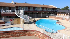 A hotel with a swimming pool, outdoor seating, and a fenced balcony. - Friendship Inn (Altus)