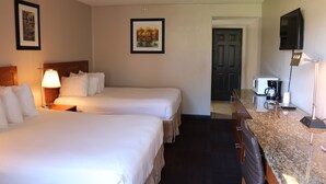 A hotel room with two beds, a desk, a television, and a door leading to another room. - Friendship Inn (Altus)