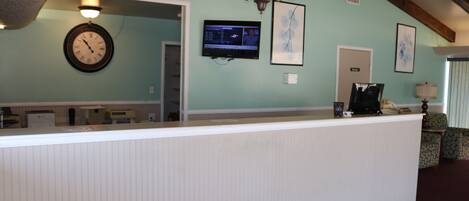A reception area with a clock, a television, and framed artwork on the wall.
