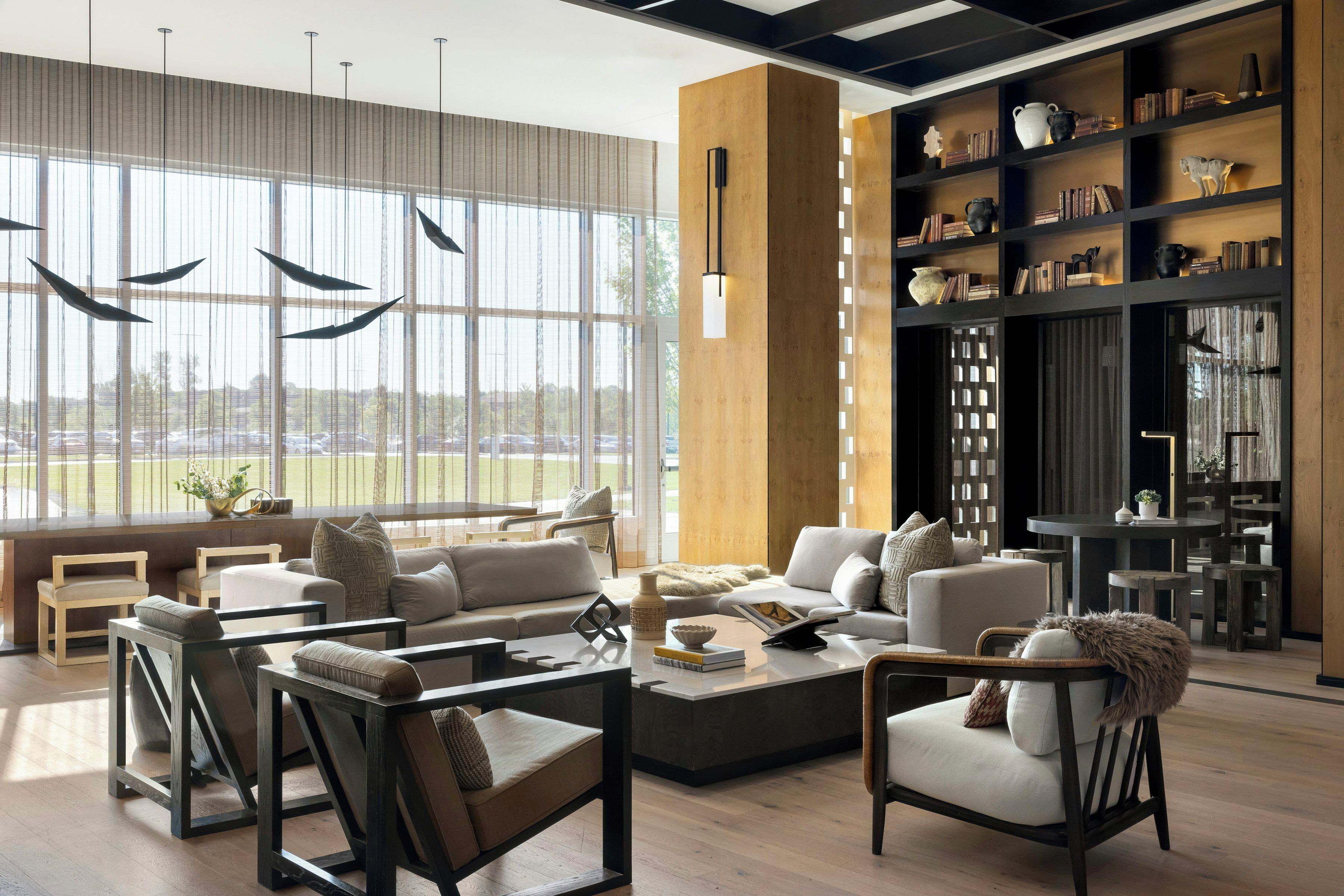 A modern living room with a large window, a bookshelf, and a seating area with sofas and chairs.