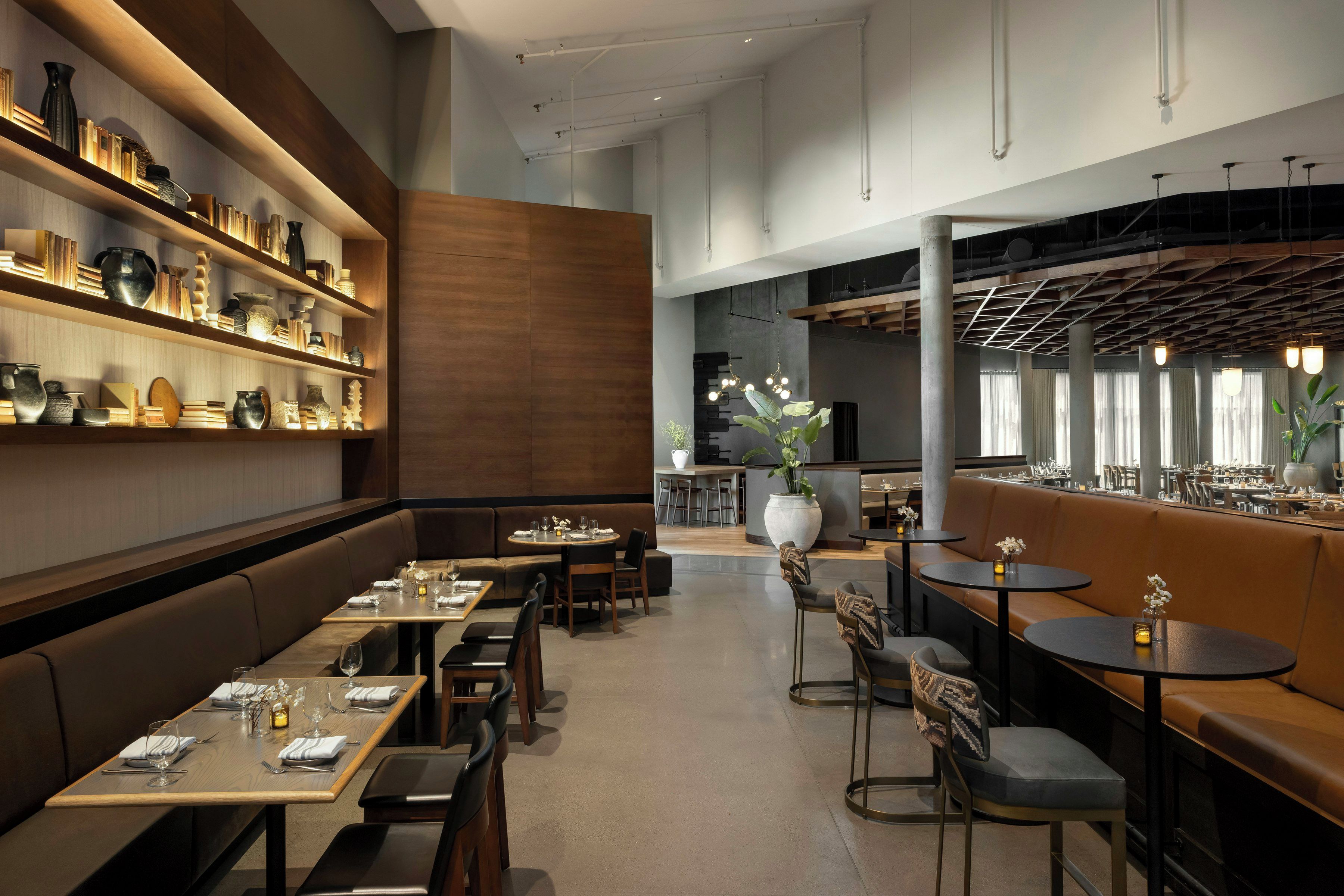 A modern restaurant interior with wooden shelves, seating arrangements, and a bar area.