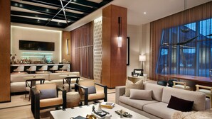 Una sala de estar moderna con un sofá, sillones, una mesa de centro y una zona de comedor con barra.