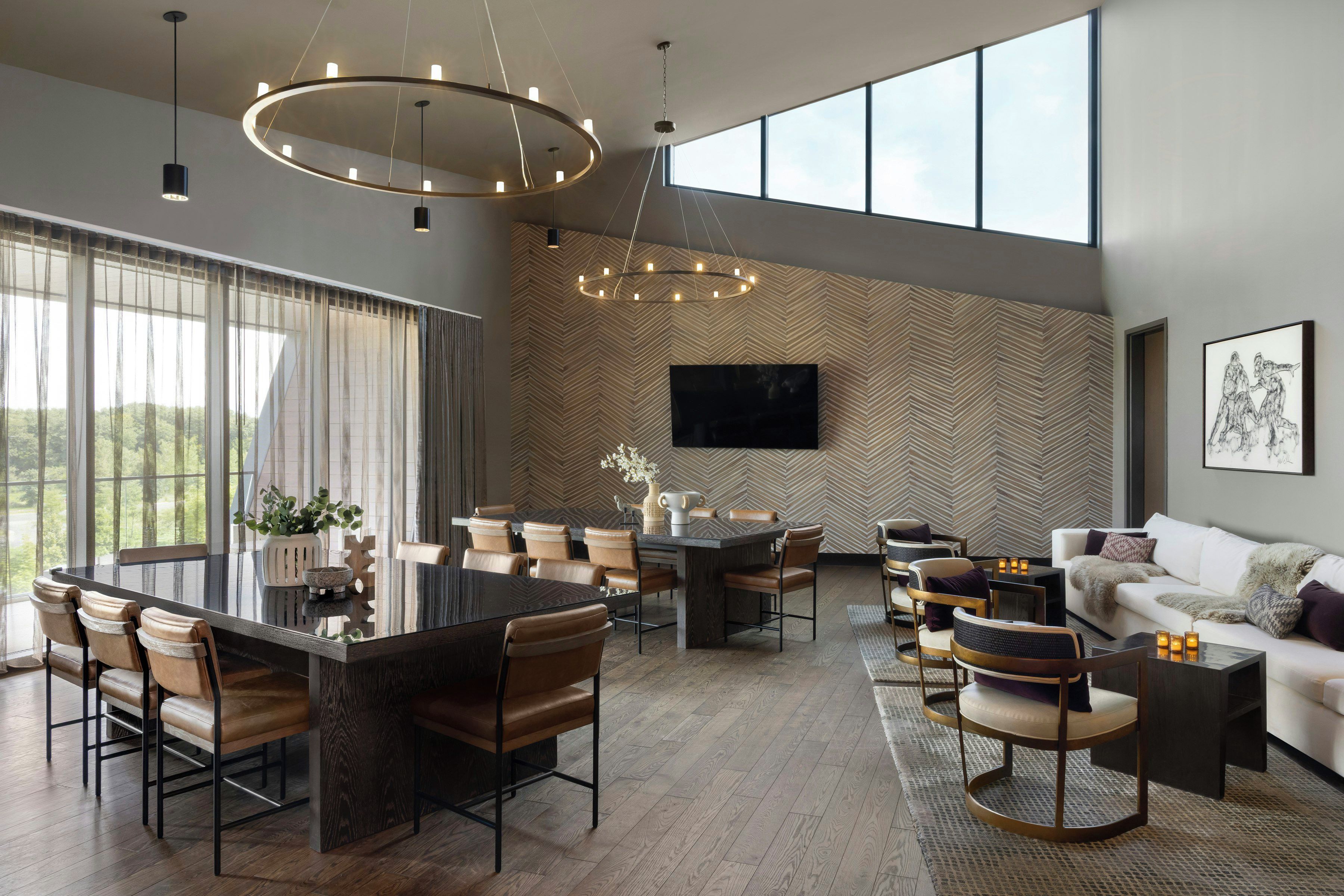 A modern living room with a dining area, large windows, and a herringbone-patterned wall.