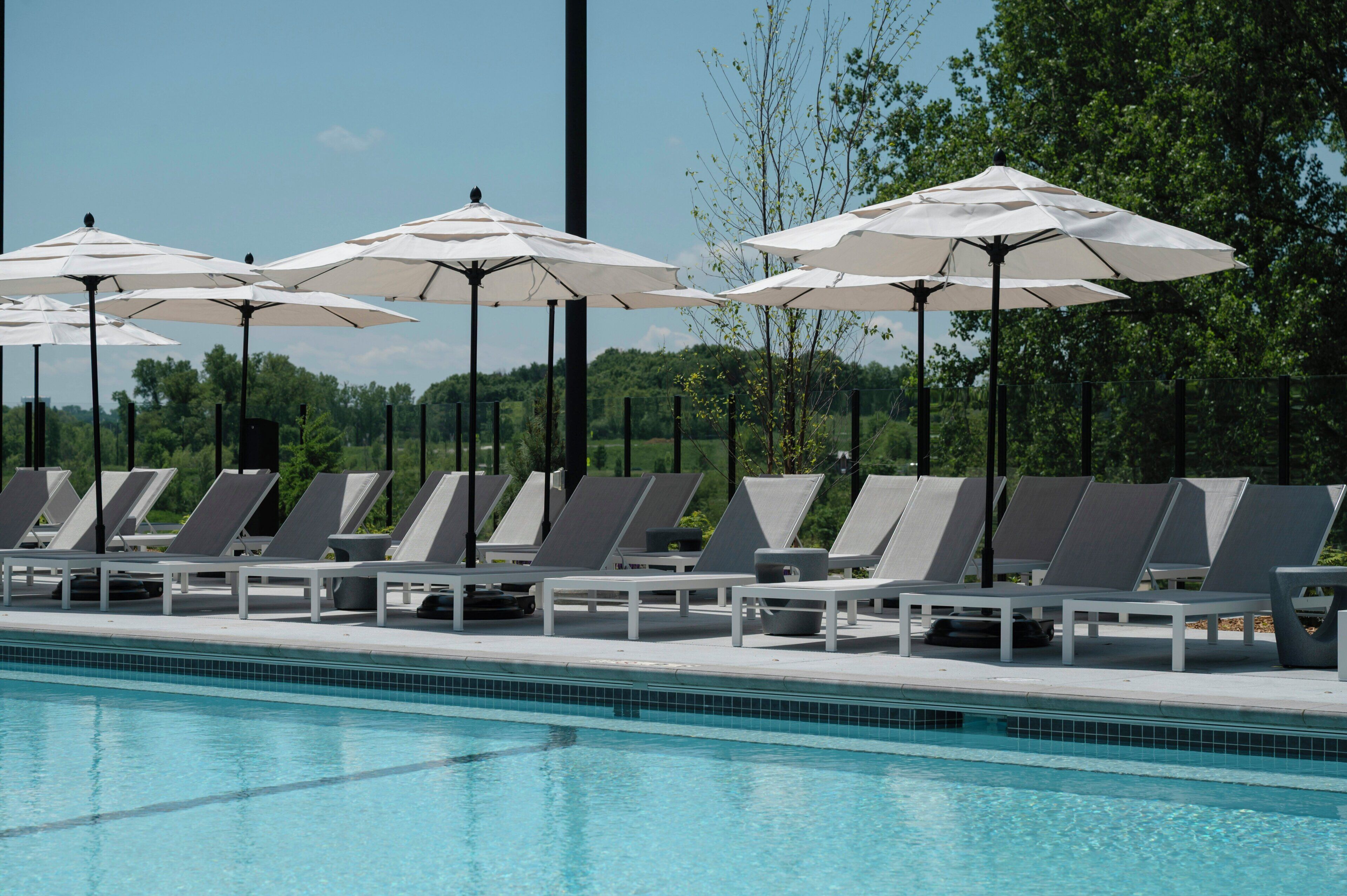 A swimming pool with lounge chairs and umbrellas.