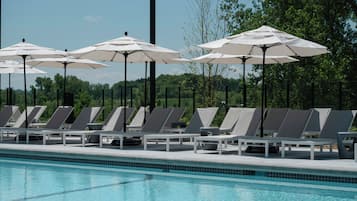A swimming pool with lounge chairs and umbrellas.