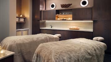 Experience ultimate relaxation in this serene spa room, featuring two treatment areas with plush benches and self-service amenities.