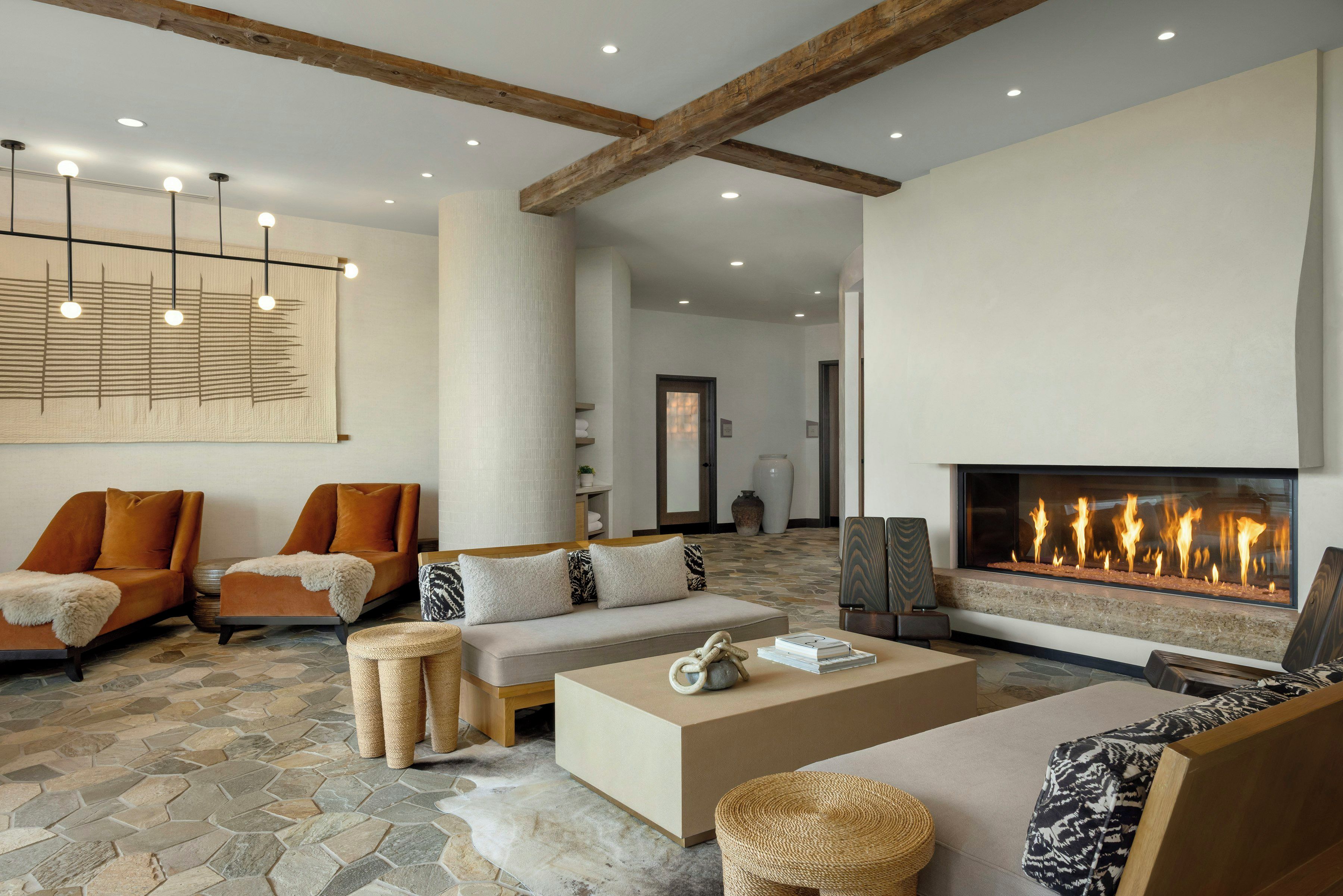 Amplia sala de estar con chimenea, muebles modernos y piso de baldosas de piedra.