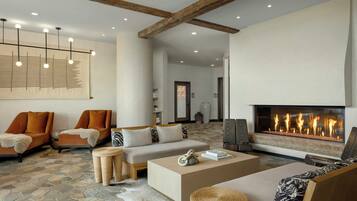 Amplia sala de estar con chimenea, muebles modernos y piso de baldosas de piedra.