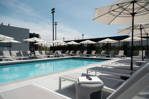 A swimming pool with lounge chairs and umbrellas, surrounded by a modern building. - Omni Viking Lakes Hotel (Eagan)