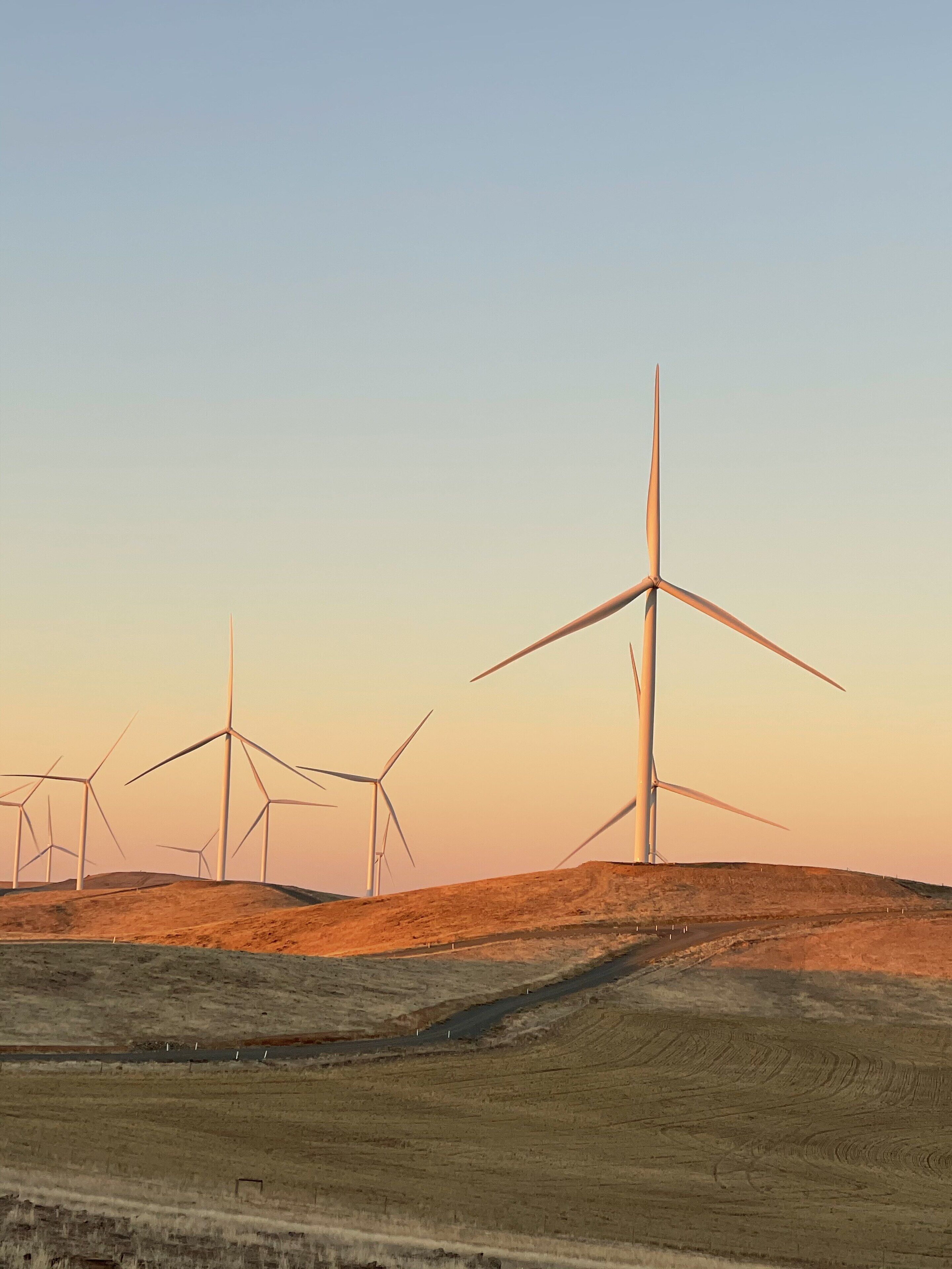 A landscape with multiple wind turbines on a hill.