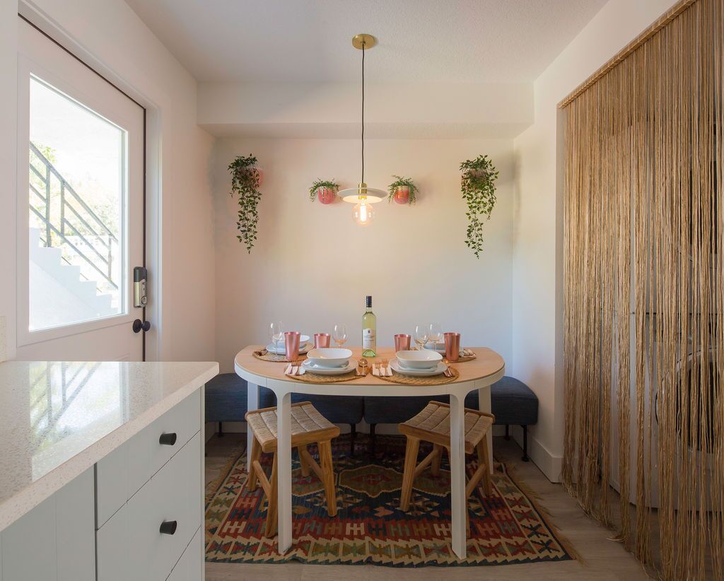 A dining area with a round table, chairs, and hanging plants.