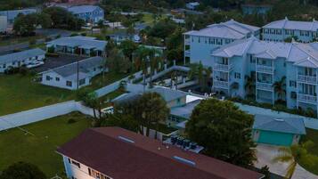 An aerial view of a residential area with houses, a large body of water, and distant buildings.