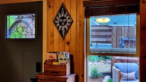 Interior de madera con un vitral, un adorno en la pared y vista a un jardín a través de una ventana.