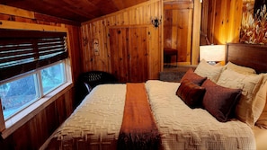 Una habitación con paneles de madera, una cama, una silla y un ventanal.