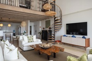 Un salón amplio con un sofá blanco, una mesa de centro de madera y una escalera de caracol.