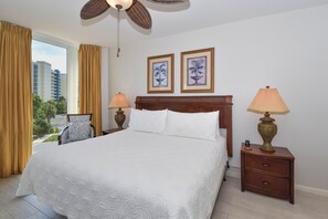 A hotel room with a large bed, two bedside lamps, a wooden nightstand, and a ceiling fan.