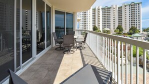 Ein Balkon mit Tisch, Stühlen, einer Glastür und Blick auf hohe Gebäude.