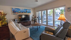 Ein Wohnzimmer mit Fernseher, Ledersofas, einem Couchtisch und einem Strandbild.