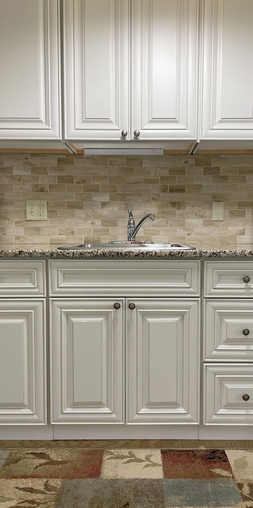 A kitchen with white cabinetry, a tiled backsplash, and a granite countertop.