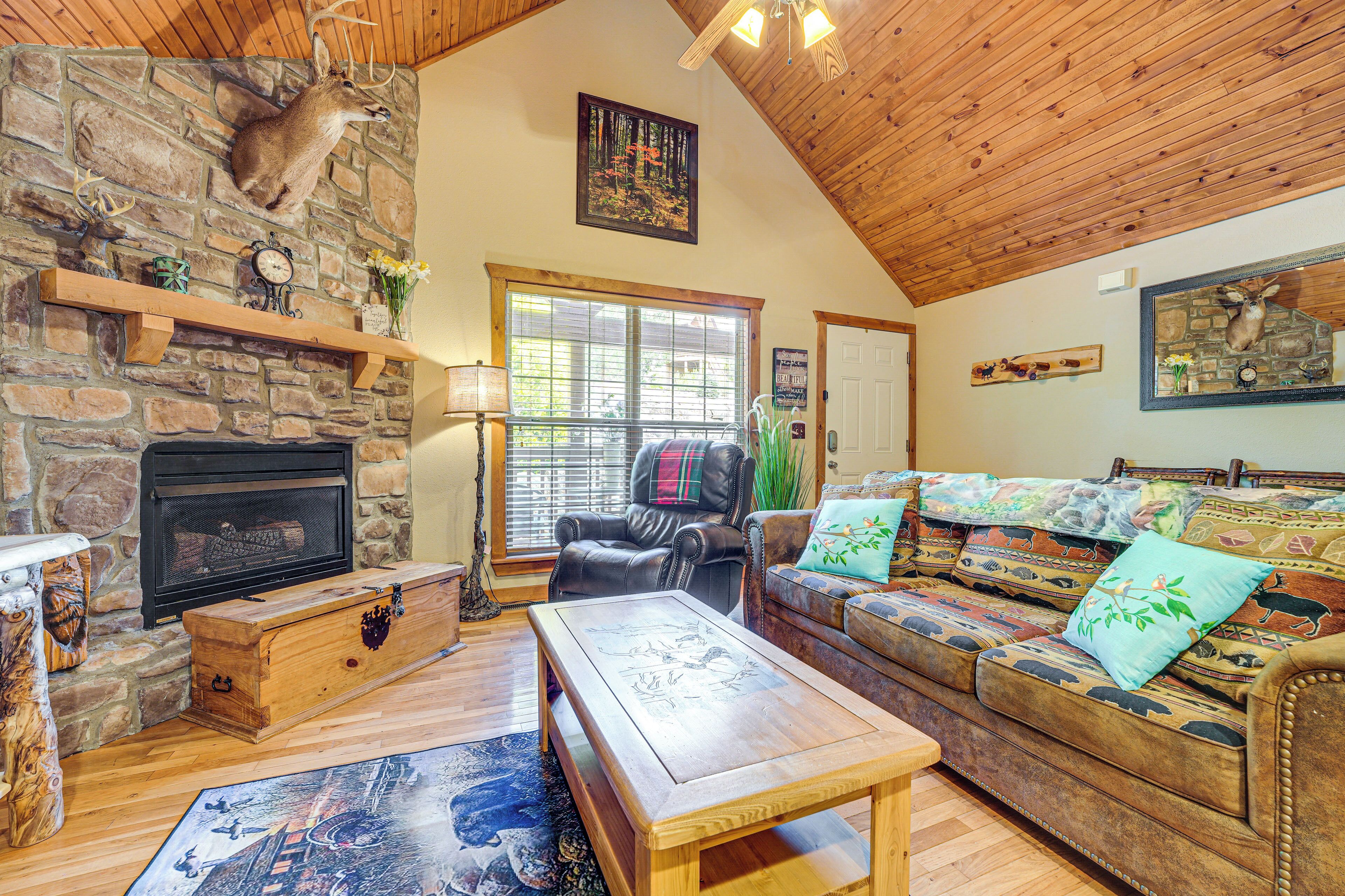 A cozy living room with a stone fireplace, leather furniture, and a large window.