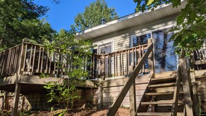 A wooden deck with a staircase leading to a house. - Treehouse on the river. (Au Train)