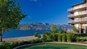 Um campo de golfe com vista para um lago e montanhas ao fundo.
