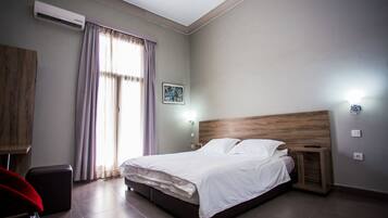 Une chambre moderne avec un grand lit, une tête de lit en bois, une table de chevet et un bureau avec une chaise.