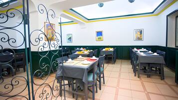 Un comedor con mesas dispuestas para comidas, sillas y un separador decorativo de metal.