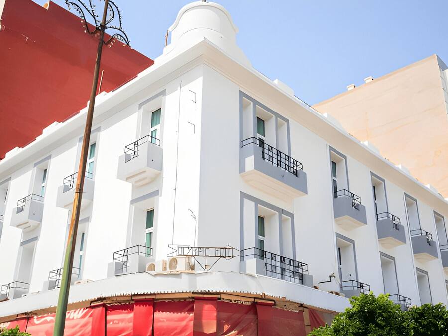 A multi-story building with balconies, a red awning, and a clear sky.