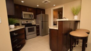 Una cocina moderna con armarios de madera oscura, electrodomésticos de acero inoxidable y encimera de granito.