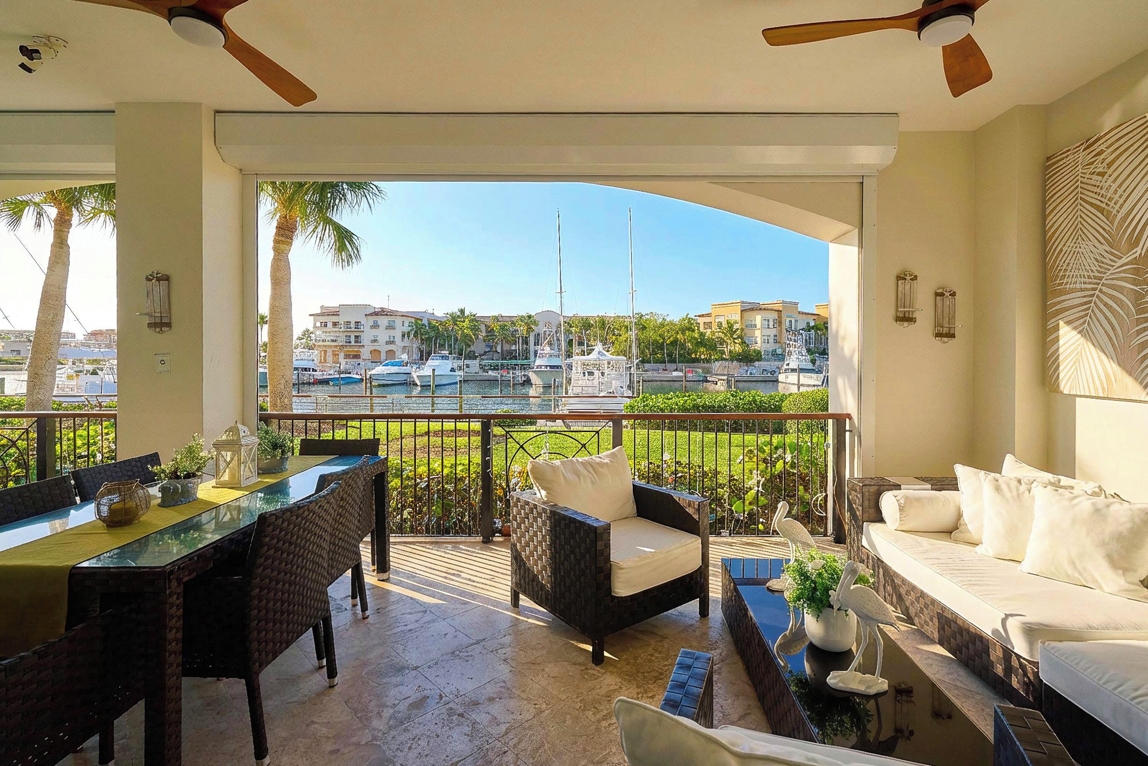 A balcony with a glass table, wicker chairs, and a white sofa.