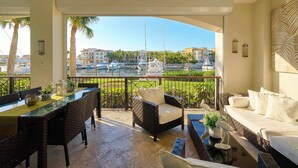 A balcony with a glass table, wicker chairs, and a white sofa.