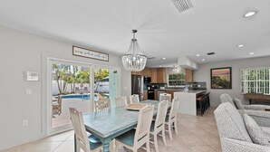 A spacious kitchen with modern appliances, a dining area with a large table and chairs, and a view of a pool through the glass door. - Single Level Home- 1 Minute Walk to the Beach- 5 minute walk to Restaurant/Shops (Holmes Beach)