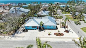 A residential area with a house featuring a blue roof, surrounded by palm trees and a clear view of the ocean. - Single Level Home- 1 Minute Walk to the Beach- 5 minute walk to Restaurant/Shops (Holmes Beach)
