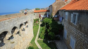 Eine steinerne Festung mit Bogenpassagen, angrenzende Wohngebäude mit roten Ziegeldächern und freiem Blick auf das Meer.