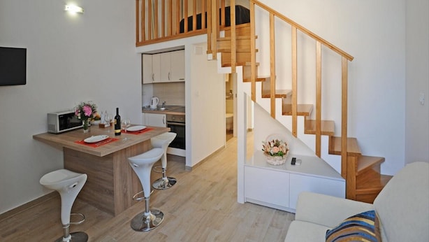 Eine moderne Wohnung mit Küche, Essbereich und einer Holztreppe.