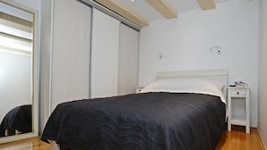 Ein Schlafzimmer mit einem Bett, einem Nachttisch, einem Spiegel und einer Schiebetür.