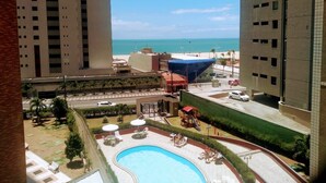 A high-rise building with a swimming pool, palm trees, and a view of the ocean. - Excellent fit 2 bedrooms fully furnished, cable TV, sea view from the balcony (CE)