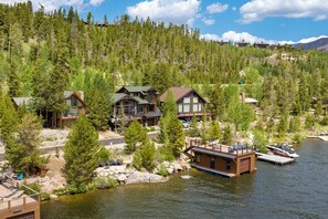 Un ensemble de chalets situés au bord d’un lac, comprenant plusieurs bâtiments, un quai et une forêt environnante.