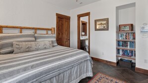 A bedroom with a bed, wooden headboard, a bookshelf, and a ceiling fan. - Stunning Lake Views with private boathouse deck, hot tub and close walk to town (Grand Lake)
