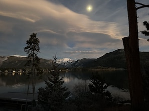 Ein See mit Bergen im Hintergrund und einem Baum im Vordergrund.