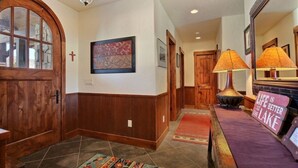 A hallway with wooden doors, a cross on the wall, and a rug with a floral pattern. - Stunning Lake Views with private boathouse deck, hot tub and close walk to town (Grand Lake)