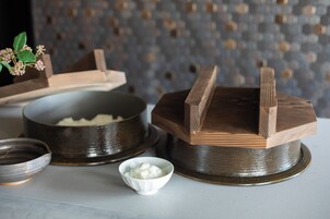 A traditional Japanese tea ceremony setup with a wooden tea bowl, a smaller bowl of rice, and a tea caddy.