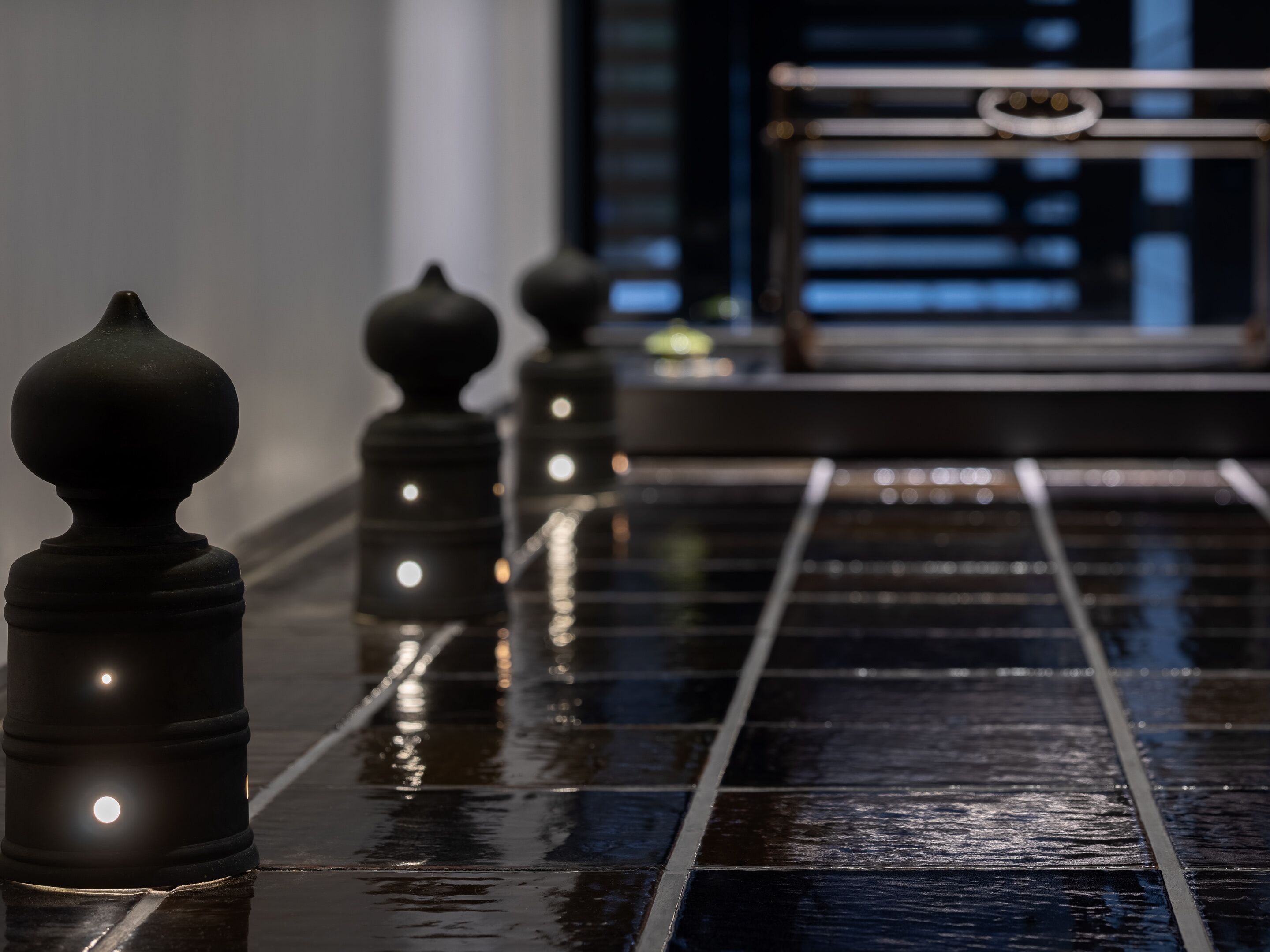 Un sol poli recouvert de carreaux noirs réfléchissants et une série d’objets sphériques illuminés.